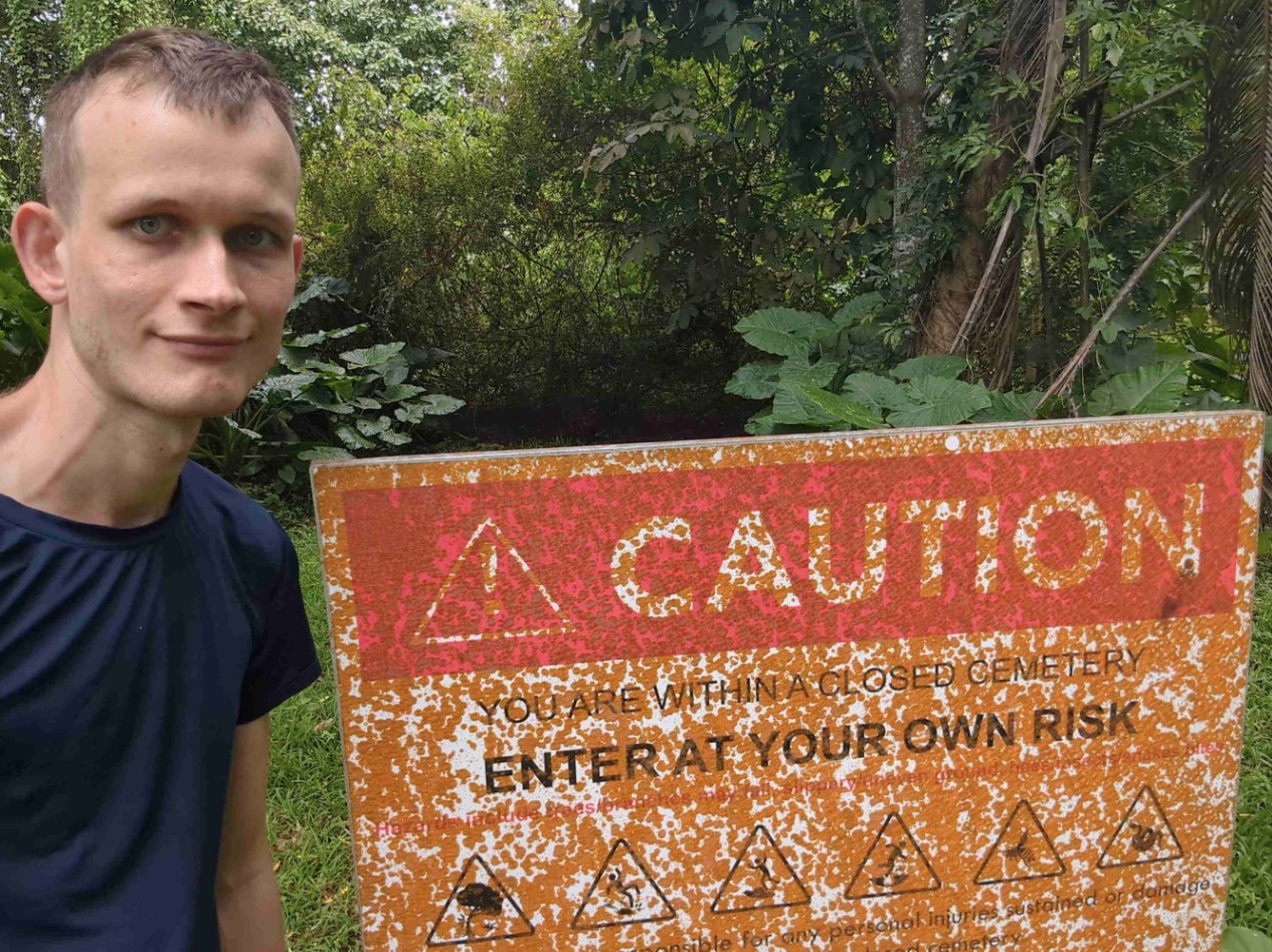 Vitalik Buterin, criador do Ethereum, ao lado de placa de perigo. Fonte: Redes sociais/Reprodução.