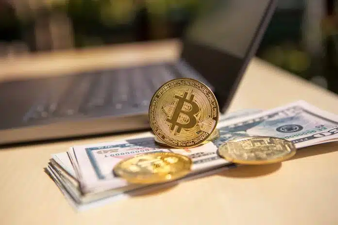Moedas de bitcoin sobre notas de dinheiro, próximo de computador