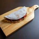 Foto de uma tapioca sobre uma tábua de madeira