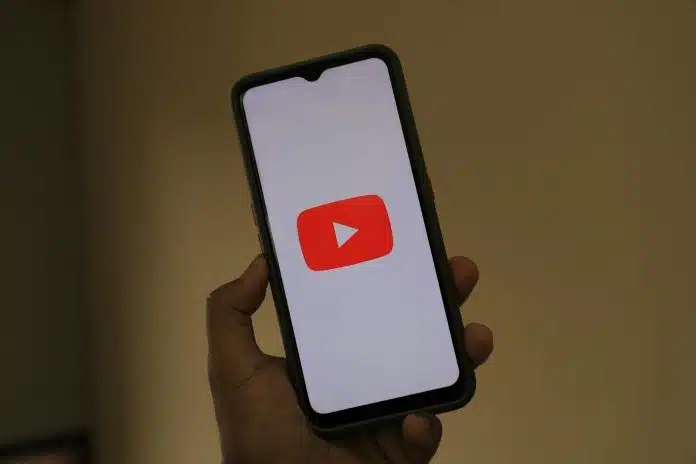 Mão de pessoa segurando celular com imagem do YouTube golpe brasil