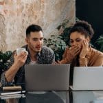 Homem e mulher olhando para tela de notebooks preocupados com o que estão vendo