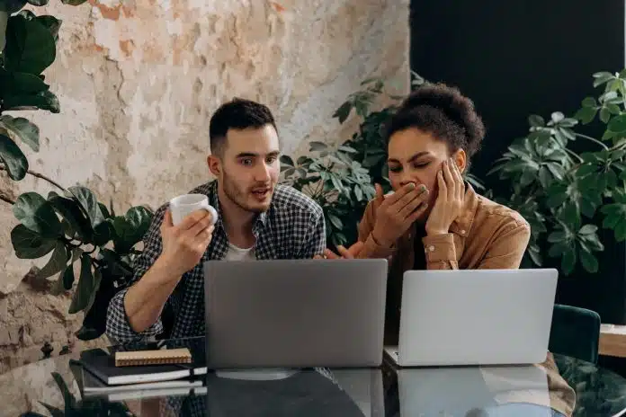 Homem e mulher olhando para tela de notebooks preocupados com o que estão vendo