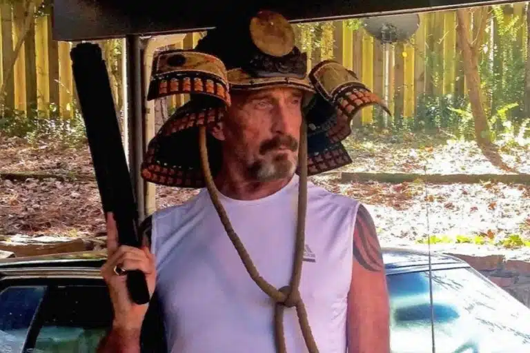 John McAfee com arma na mão e armadura samurai