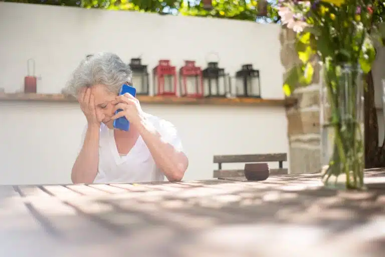 Idosa preocupada com mão na cabeça enquanto fala no telefone boomers colapso crash