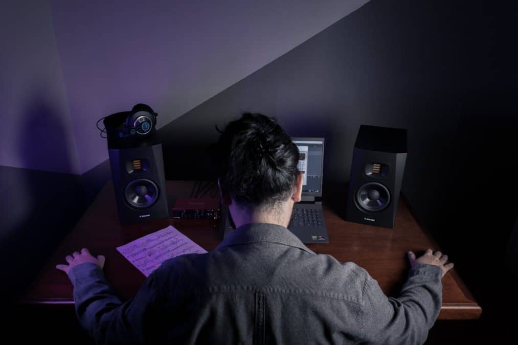 Homem com as mãos na mesa em frente a equipamentos de som hacker e criptomoedas