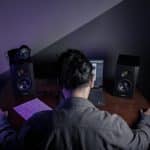 Homem com as mãos na mesa em frente a equipamentos de som hacker e criptomoedas