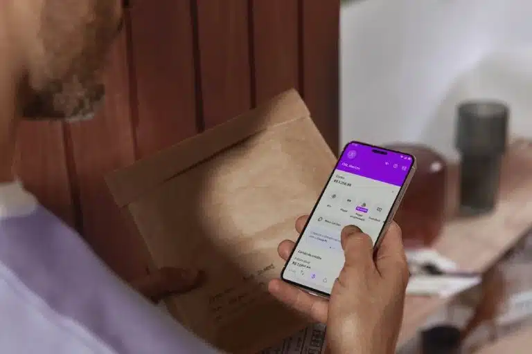 Homem segurando celular com aplicativo do Nubank aberto