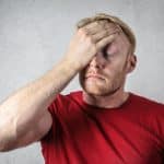 Homem com mãos na cabeça lamentando situação