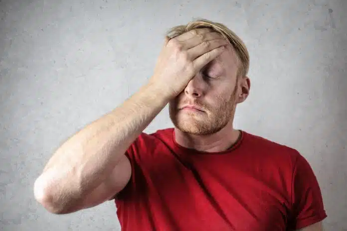 Homem com mãos na cabeça lamentando situação