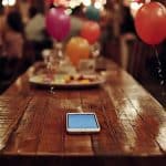 Smartphone esquecido sobre mesa em festa de aniversário. Fonte: Midjourney.