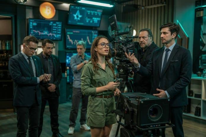Equipe de filmagens de cinema próximos de gráficos de criptomoedas e símbolo do bitcoin