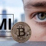 Homem olha atento ao bitcoin próximo de placa do FMI, o Fundo Monetário Internacional