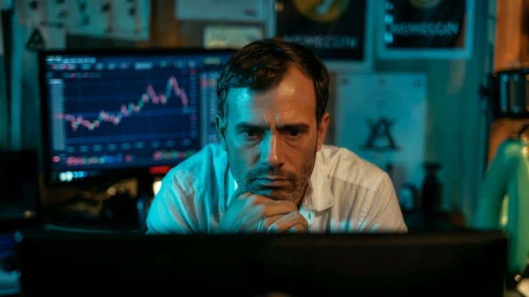 Investidor sério ao assistir live, com gráfico de criptomoedas ao fundo