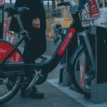 Mulher segurando bicicleta na rua com símbolo do Santander