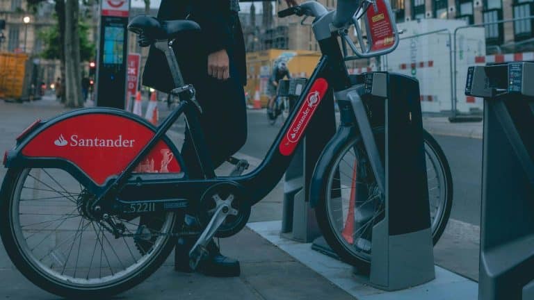 Mulher segurando bicicleta na rua com símbolo do Santander