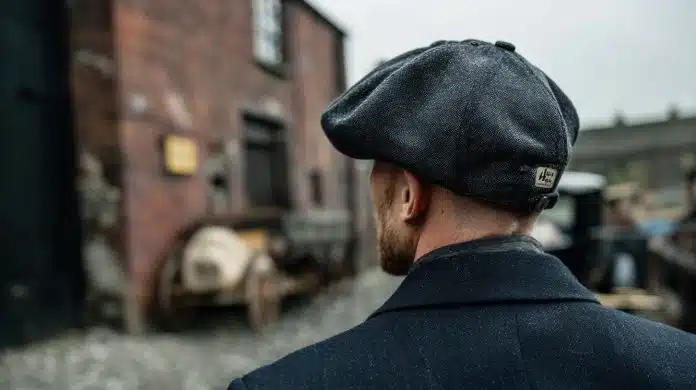 Homem usando boina inglesa, comum na série Peaky Blinders. Fonte: Midjourney.