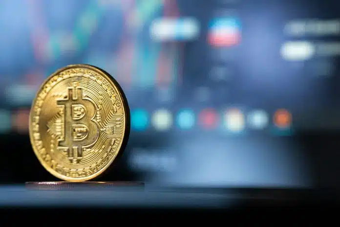 Bitcoin com tela de negociação ao fundo