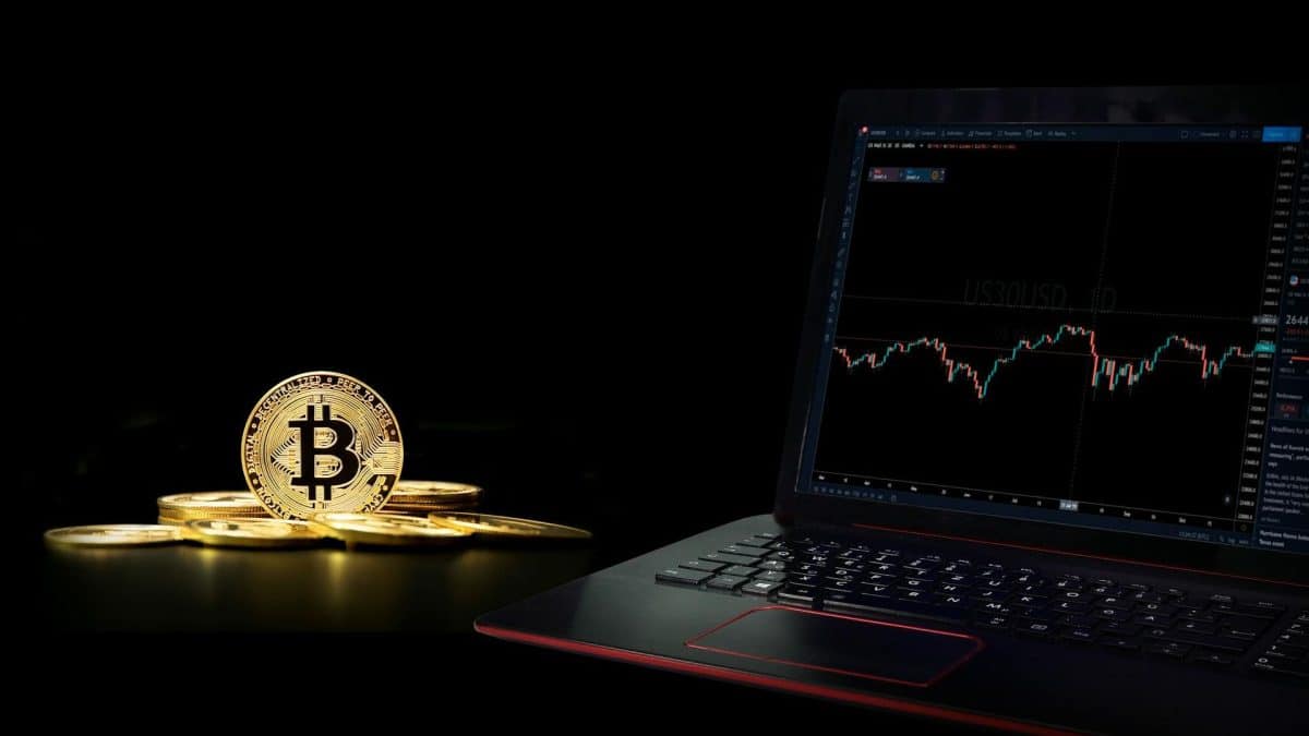 Monte de bitcoin sobre mesa ao lado de notebook
