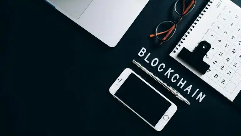 Palavra blockchain em destaque sobre a mesa em meio a itens