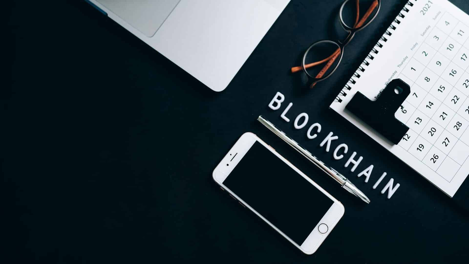 Palavra blockchain em destaque sobre a mesa em meio a itens