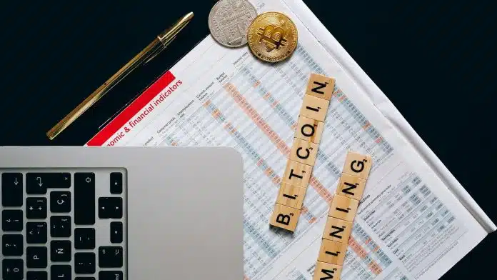 Quadrados de madeira escritos Mineração de Bitcoin em inglês, próximos de computador