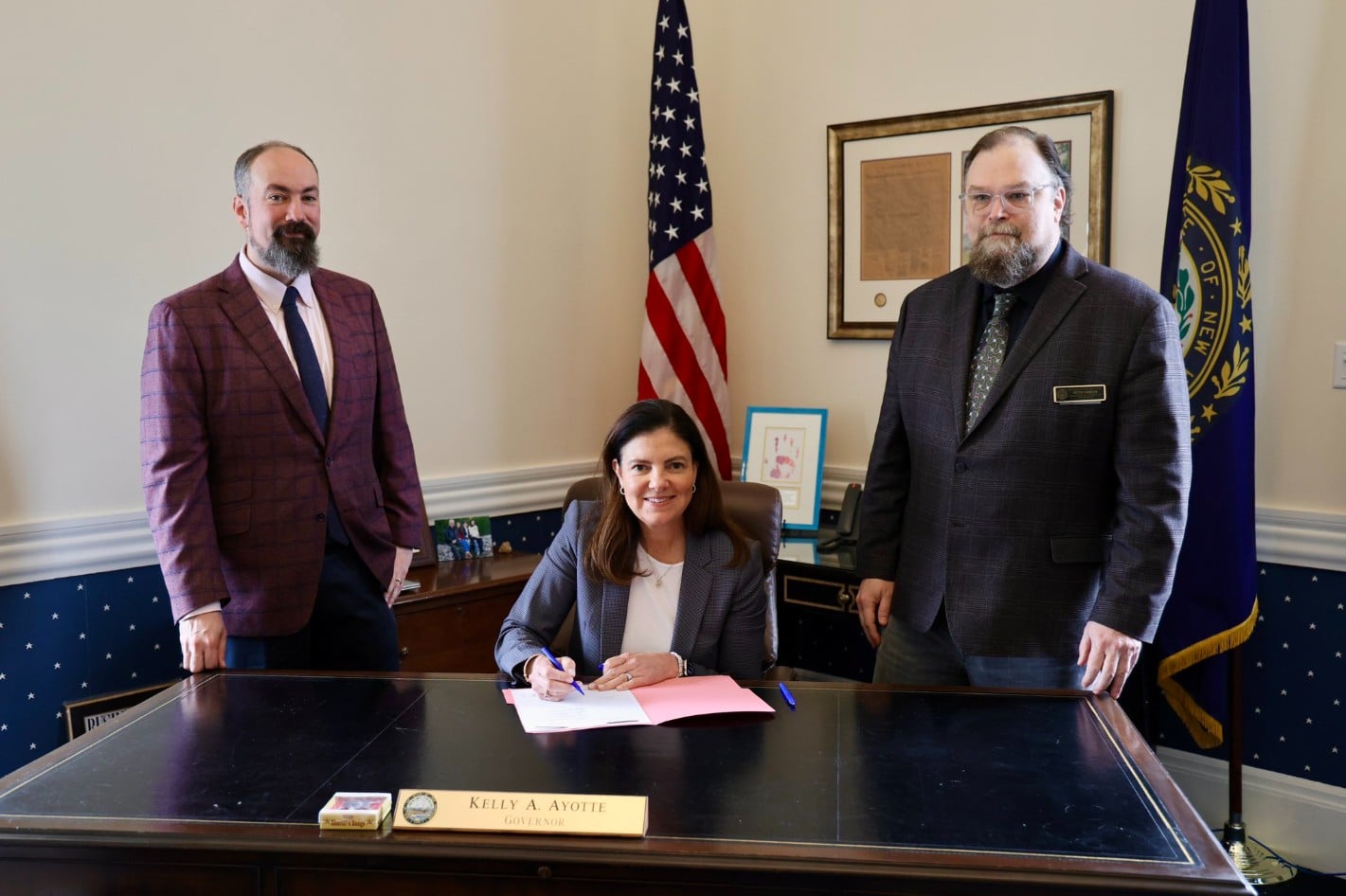 Governadora de New Hampshire, Kelly Ayotte, assinando lei que permite compra de Bitcoin por seu estado. Fonte: X.