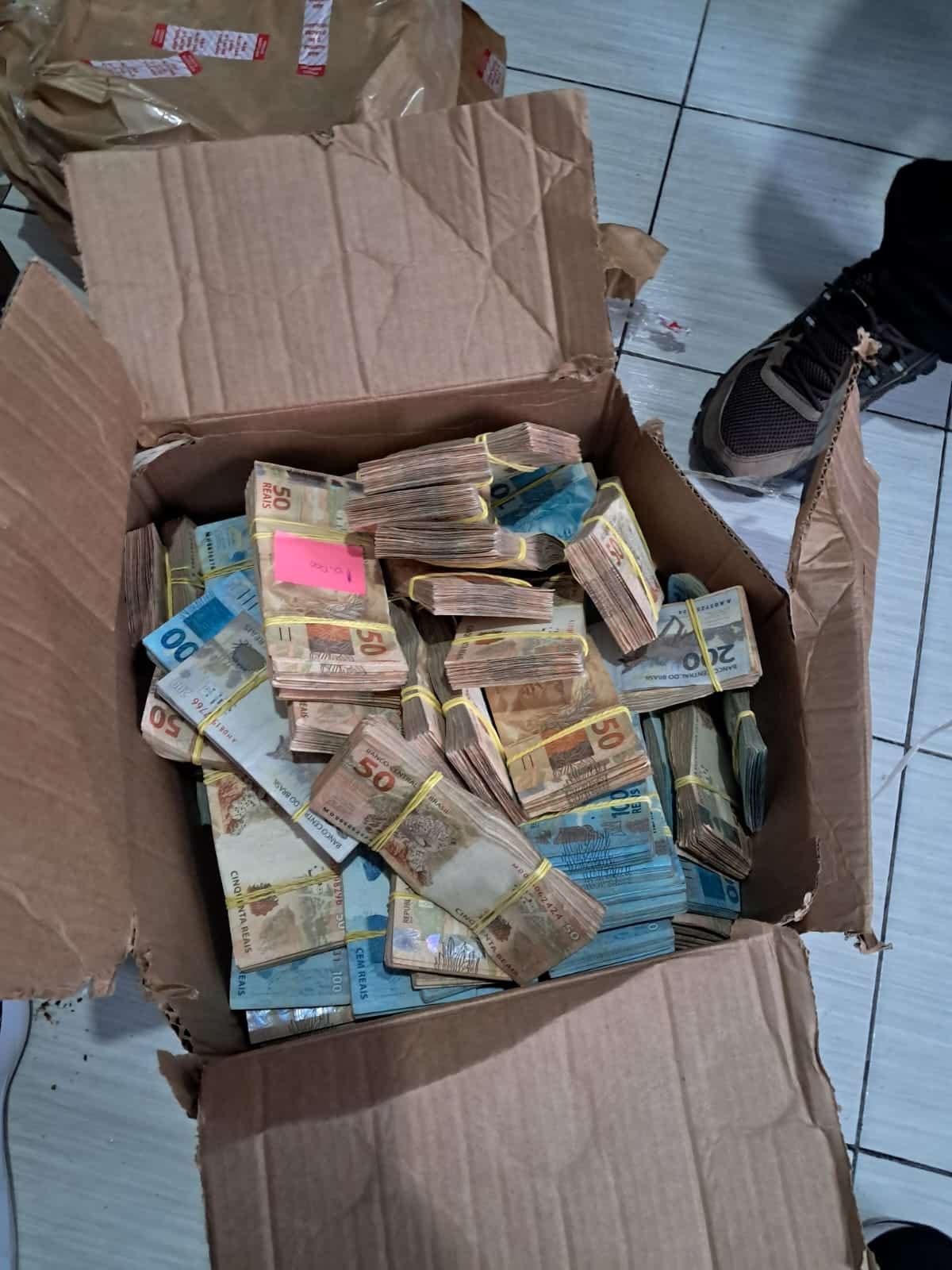 Caixa de papelão mostra montante de notas de Real apreendidos pela Polícia Civil de Rondônia