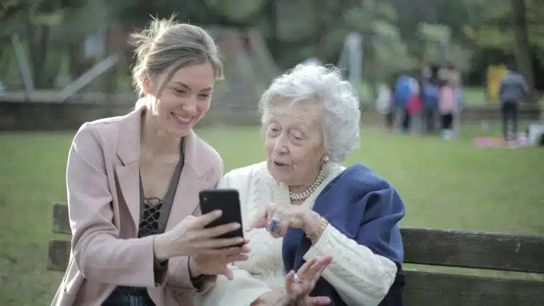Filha e mãe felizes ao mexer em dispositivo eletrônico bitcoin e criptomoedas aposentadoria