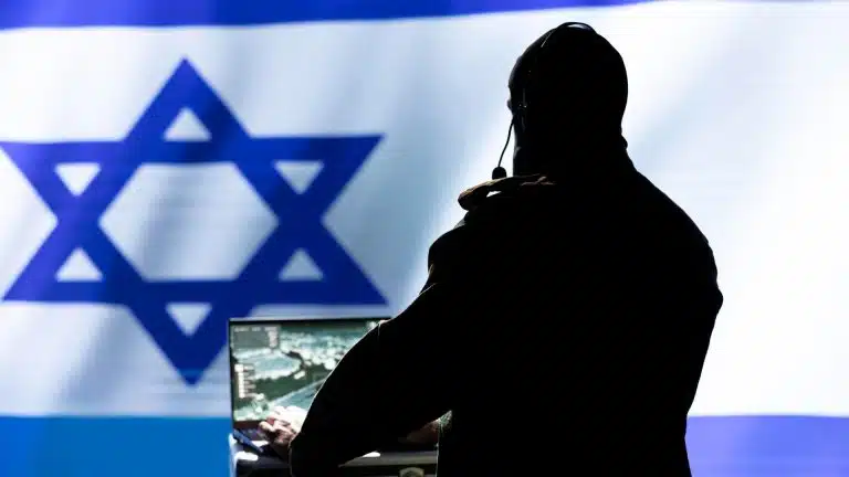 Homem com computador ligado em frente a bandeira de Israel criptomoedas Irã