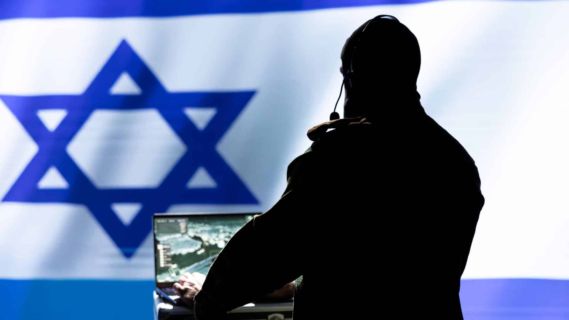Homem com computador ligado em frente a bandeira de Israel criptomoedas Irã