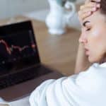 Jovem preocupada com queda nos gráficos de investimentos vender criptomoedas prejuízo bitcoin