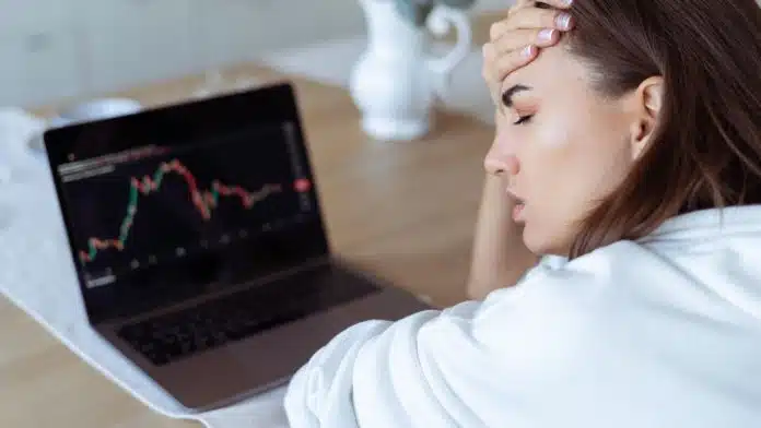 Jovem preocupada com queda nos gráficos de investimentos vender criptomoedas prejuízo bitcoin