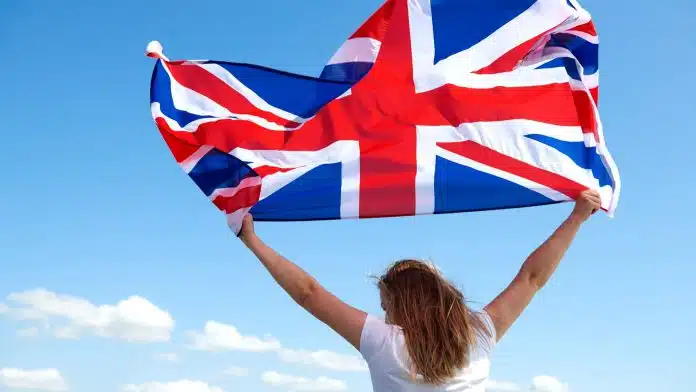 Mulher segurando bandeira do Reino Unido ao vento rastrear criptomoedas bitcoin