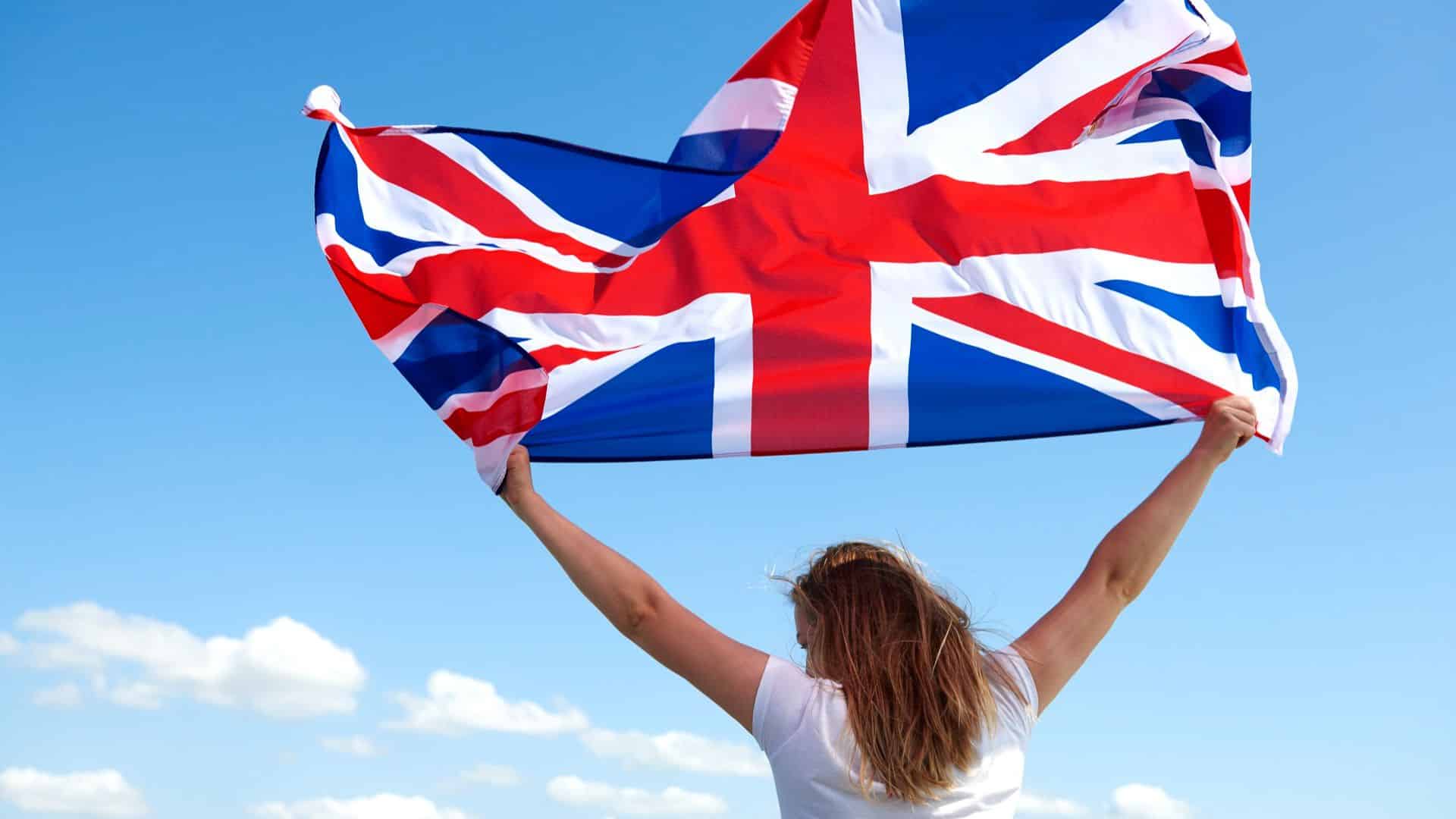 Mulher segurando bandeira do Reino Unido ao vento rastrear criptomoedas bitcoin