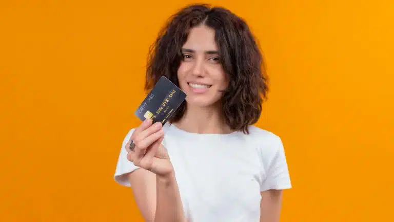 Mulher segurando cartão com fundo laranja banco do brasil brasileira criptomoedas
