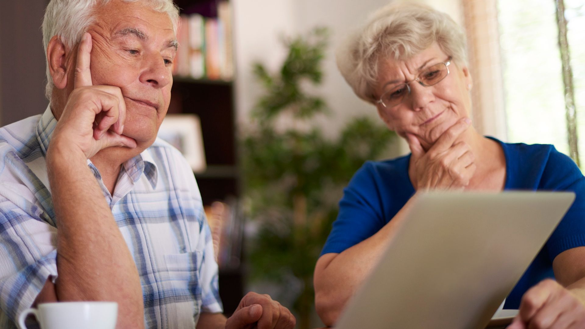 Idosos analisando computador com desconfiança golpes