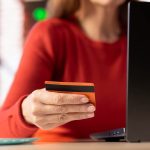 Mulher segurando cartão laranja itaú criptoativos