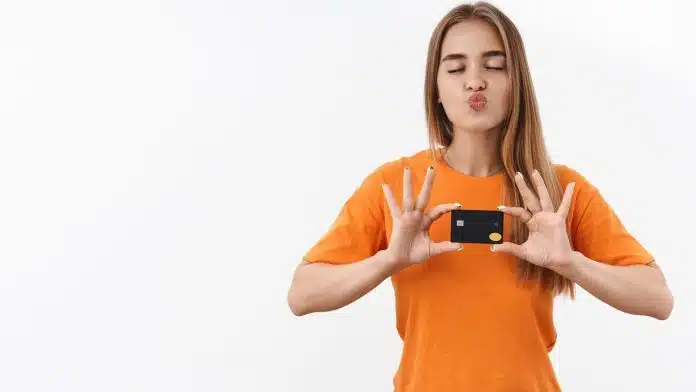 Mulher com camisa laranja segurando cartão Foxbit