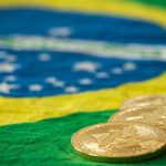 Bandeira do Brasil e moedas de bitcoin.
