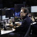 André Portilho com telas de negociação em aberto, executivo do BTG Pactual e Mynt