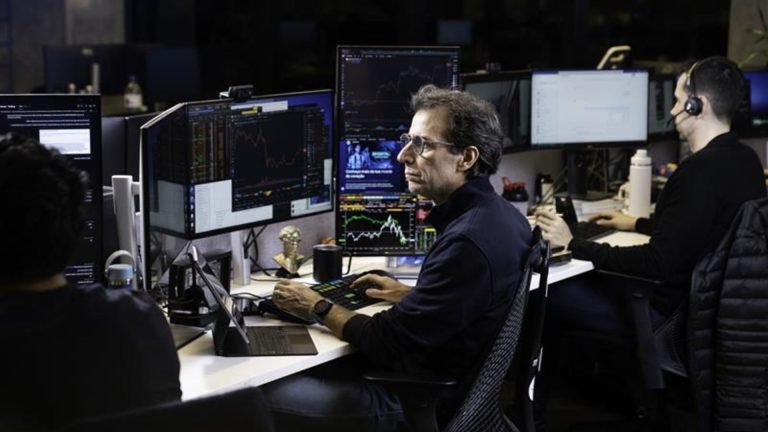 André Portilho com telas de negociação em aberto, executivo do BTG Pactual e Mynt