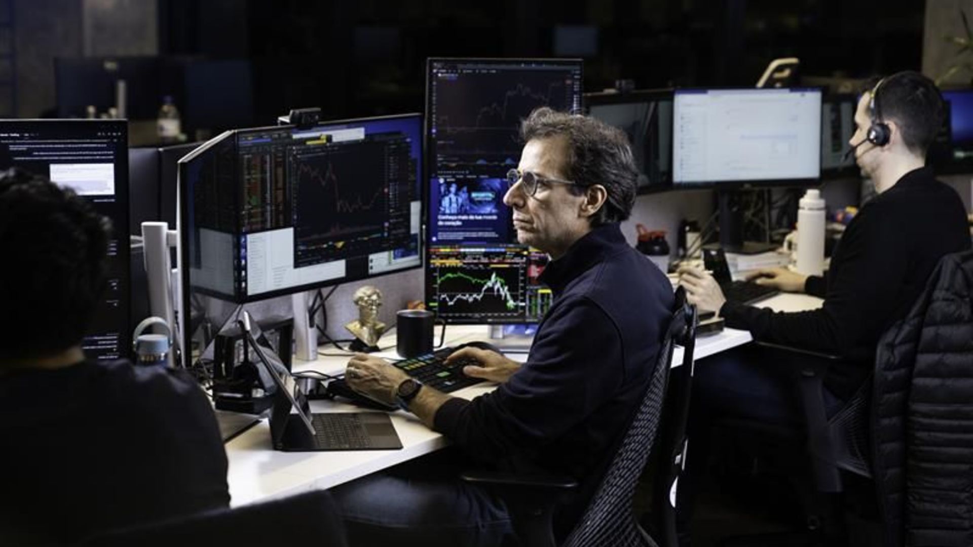 André Portilho com telas de negociação em aberto, executivo do BTG Pactual e Mynt