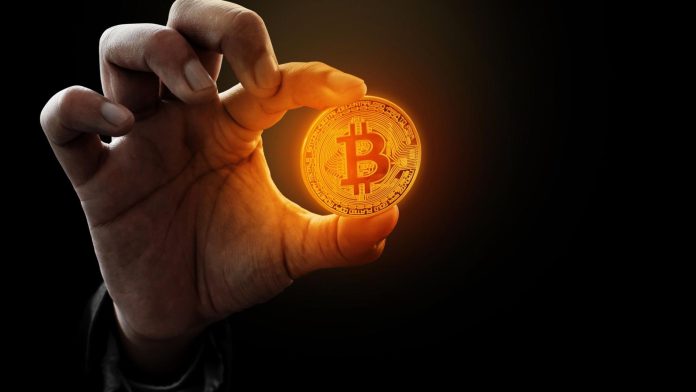 Homem segurando bitcoin em cor quente