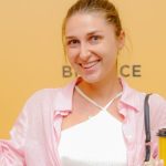 Mulher segurando copo com imagem da Binance em evento