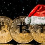 Bitcoins um ao lado do outro, um com gorro de papai noel preço Natal