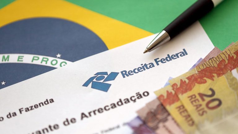 Comprovante de arrecadação da Receita Federal próximo de bandeira e dinheiro do Brasil
