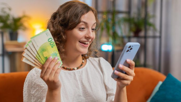 Mulher animada lendo celular com notas de Euro na mão stablecoin Tether