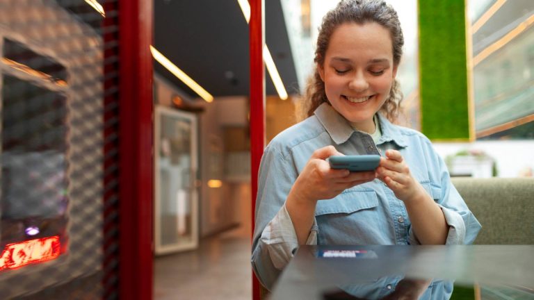 Mulher feliz ao celular com fundo vermelho Santander criptomoedas