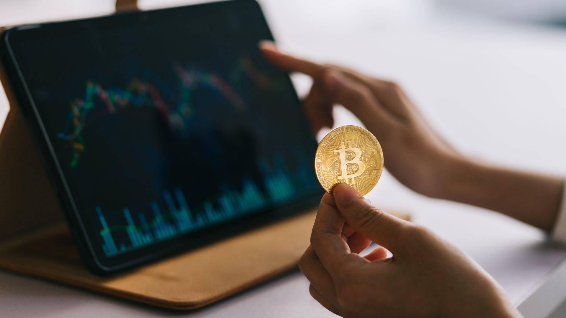 Mulher olhando gráficos com bitcoin na mão