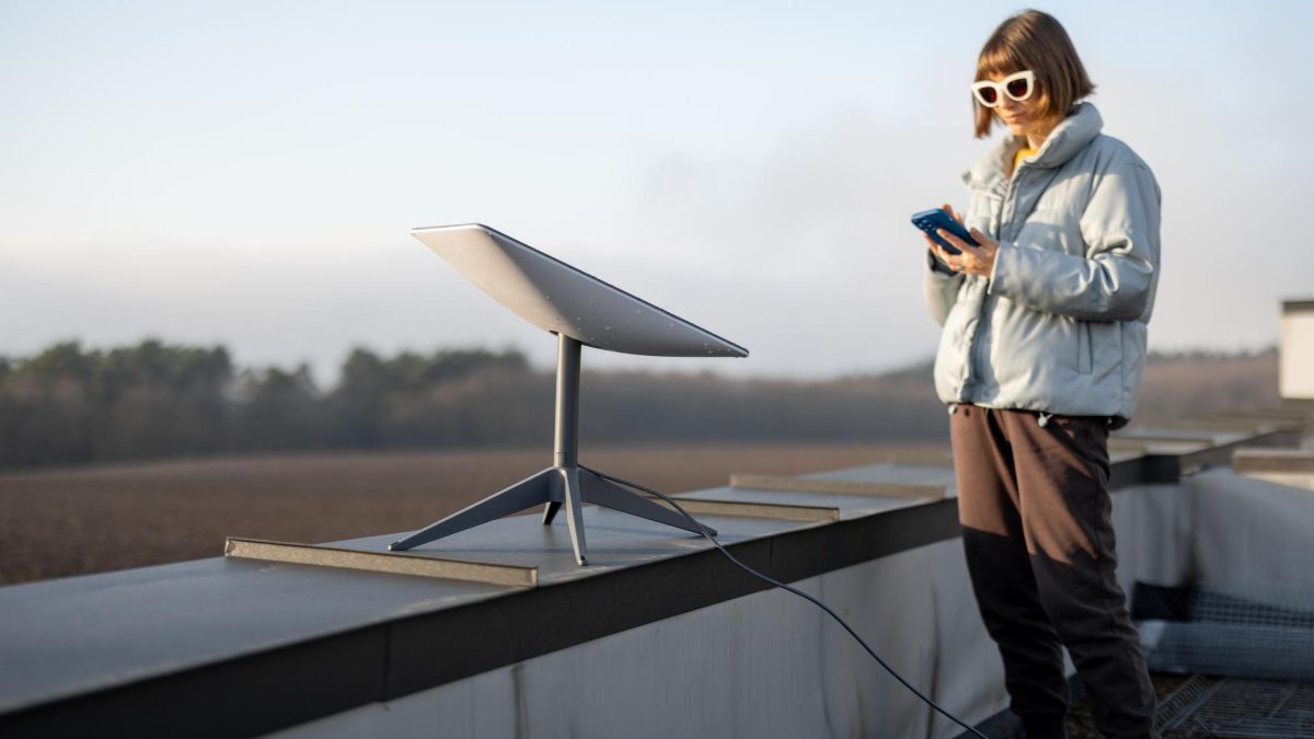 Mulher próxima de antena da Starlink